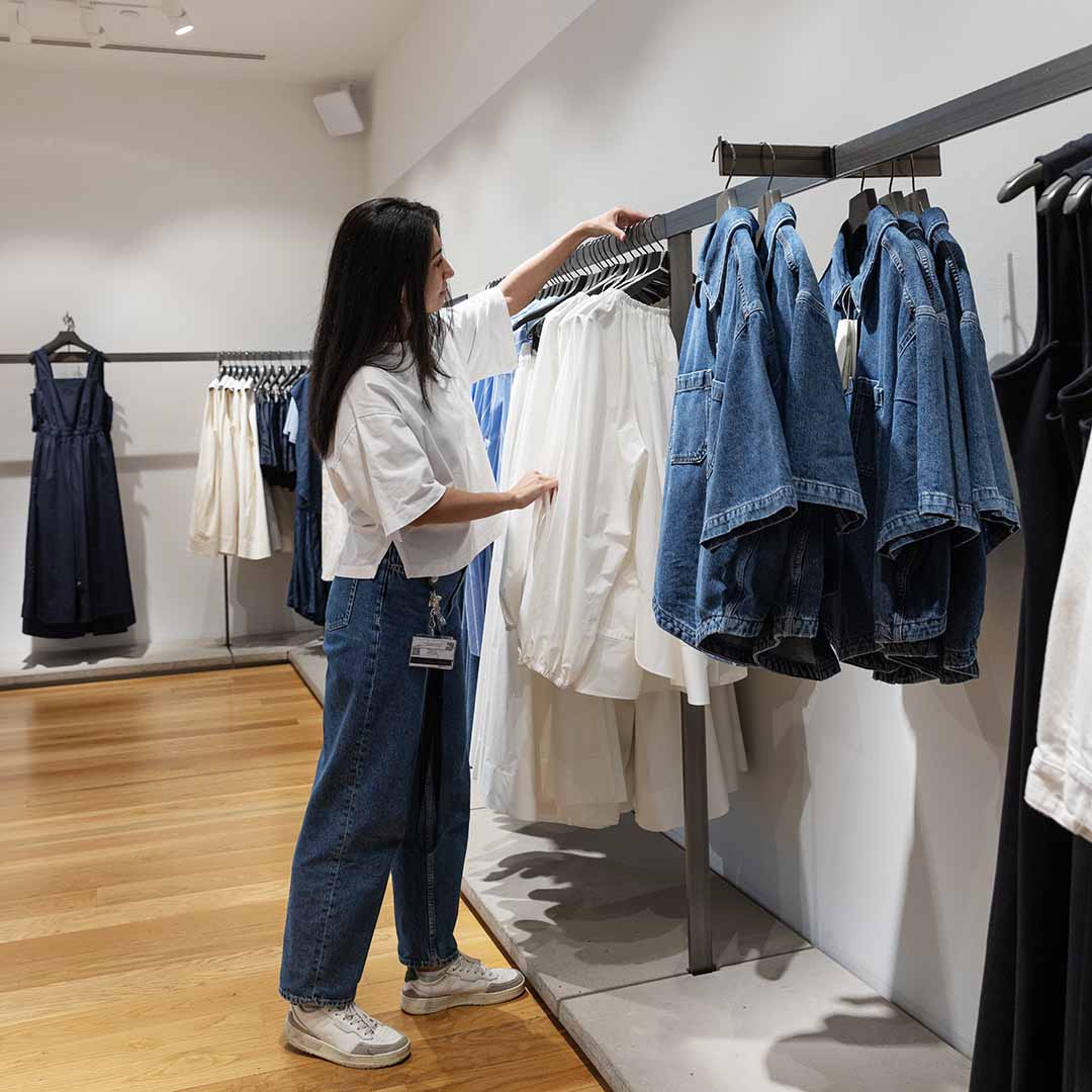 Employee from COS in Frederiksberg hangs a shirt back in place.